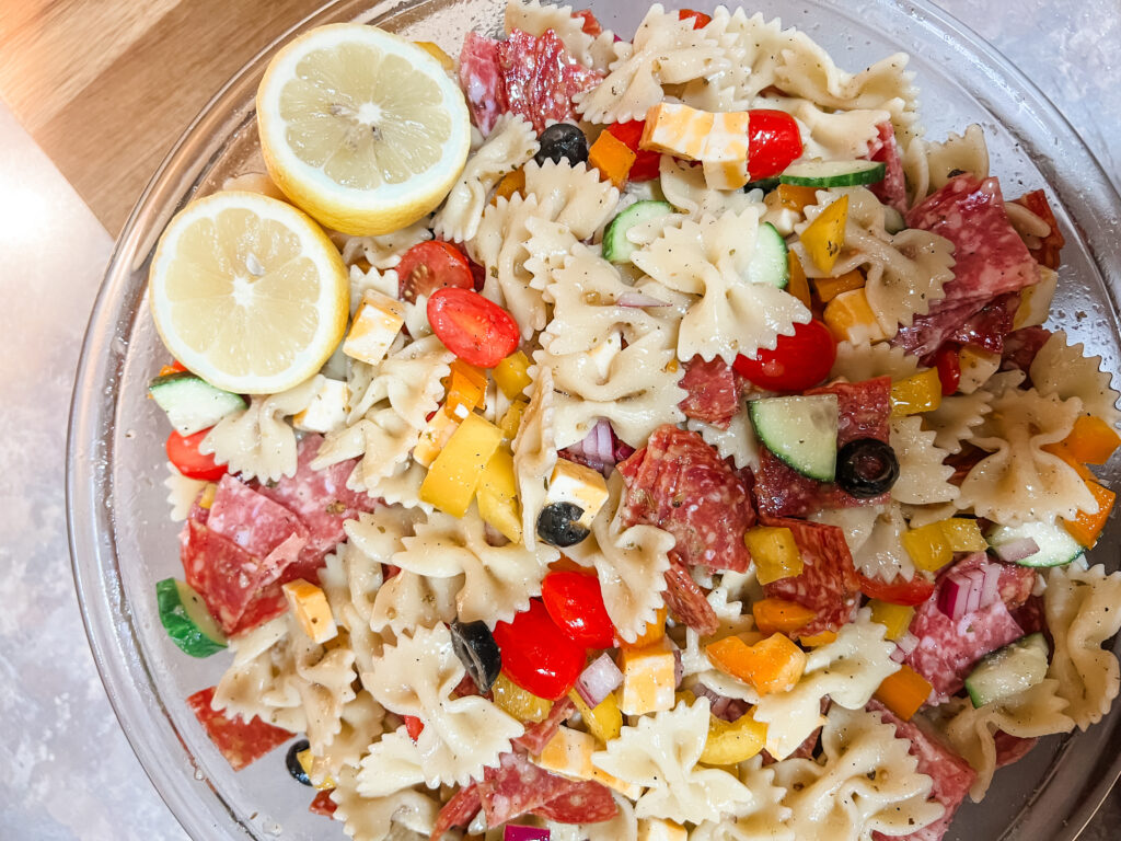 Cold summer pasta salad with lots of vegetables lemon cut in half